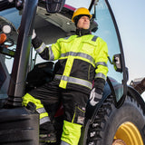 Mies seisoo traktorin portailla päällään Prihan talvivaatteet.